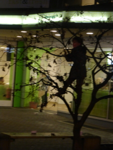 A scared but curious boy climbs a tree to see the action without risk of being whipped or kidnapped by Krampus.